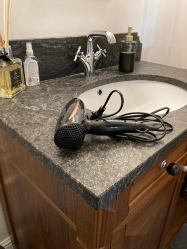 a hair dryer sitting on a counter next to a sink at Kraków Green Hill Luxury Apartment in Balice