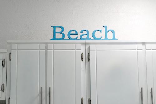a sign for a beach on top of white cabinets at Seaside Adventure Lodging in Ensenada