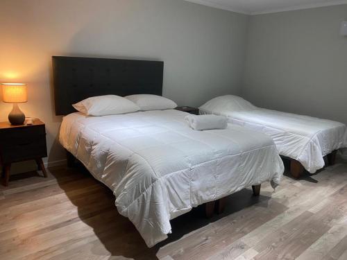 a bedroom with two beds with white sheets and a lamp at La casona Talpen in Constitución