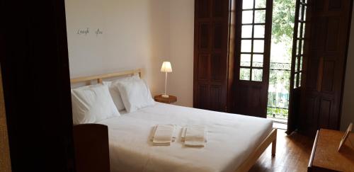 um quarto com uma cama branca com duas toalhas em Quinta de Carvalhal - Casa de Campo em Guimarães