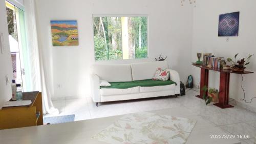a living room with a white couch and a window at Recanto Sananda in São José dos Pinhais