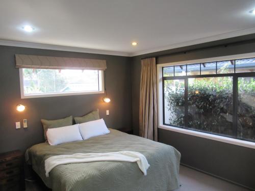 a bedroom with a bed with two pillows and a window at Palm Paradise in Tauranga