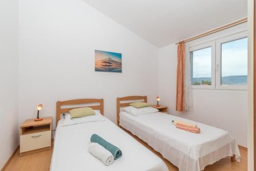 two beds in a room with a window at Apartments with a parking space Slatine, Ciovo - 16732 in Slatine