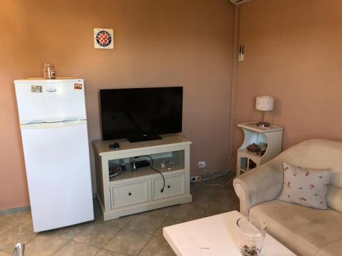 ein Wohnzimmer mit einem TV und einem weißen Kühlschrank in der Unterkunft Apartment Barbat 16723b in Rab