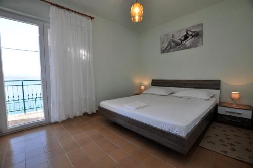 ein Schlafzimmer mit einem Bett und einem großen Fenster in der Unterkunft Family friendly seaside apartments Stanici, Omis - 16606 in Omiš