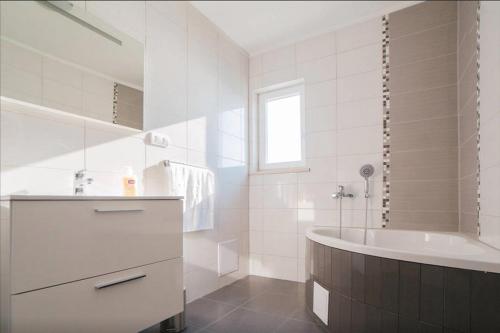 ein weißes Badezimmer mit einer Badewanne und einem Waschbecken in der Unterkunft Family friendly seaside apartments Stanici, Omis - 16606 in Omiš