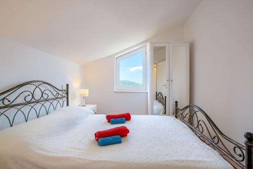 a white bed with two red and blue pillows on it at Family-friendly apartments with swimming pool Murter - 16655 in Murter