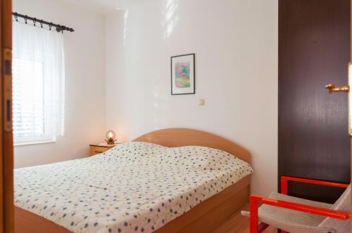 a small bedroom with a bed and a chair at Apartments by the sea Supetarska Draga - Gonar, Rab - 16738 in Rab