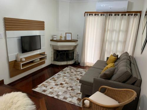 a living room with a couch and a television at Apto próximo aos pontos turísticos e restaurantes in Gramado