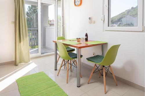 una pequeña cocina con mesa y sillas verdes en Apartments by the sea Duce, Omis - 16877, en Dugi Rat