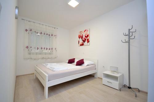 a white bedroom with a bed and a window at Apartment Tribunj 16884b in Tribunj