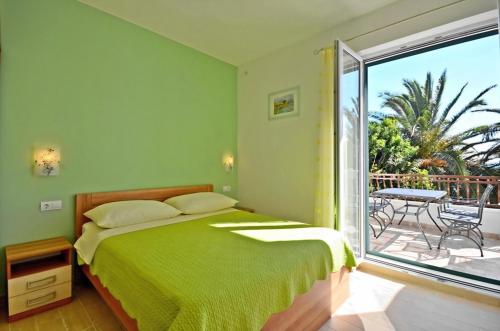 a bedroom with a green bed and a balcony at Apartments by the sea Podstrana, Split - 16829 in Podstrana