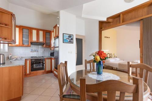 a kitchen and dining room with a table with a vase of flowers at Apartments by the sea Podstrana, Split - 16829 in Podstrana