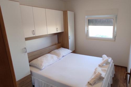una camera da letto con un letto con lenzuola bianche e una finestra di Holiday house with a parking space Ljubac, Zadar - 16964 a Ljubač