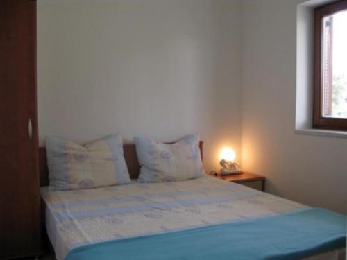 a bedroom with a bed with pillows and a window at Apartments with parking space Barbat, Rab - 16816 in Rab