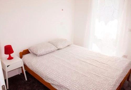 a bedroom with a bed and a red lamp on a table at Apartments by the sea Sveti Filip i Jakov, Biograd - 16966 in Sveti Filip i Jakov
