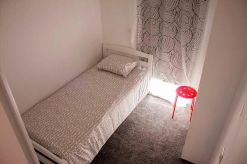 a small bedroom with a bed and a red stool at Apartments by the sea Sveti Filip i Jakov, Biograd - 16966 in Sveti Filip i Jakov