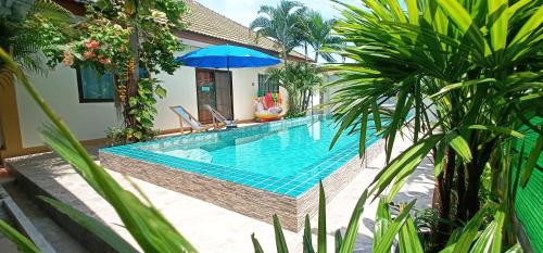 a swimming pool with a blue umbrella and some plants at Sweet Floresta Pool Villa in Sattahip