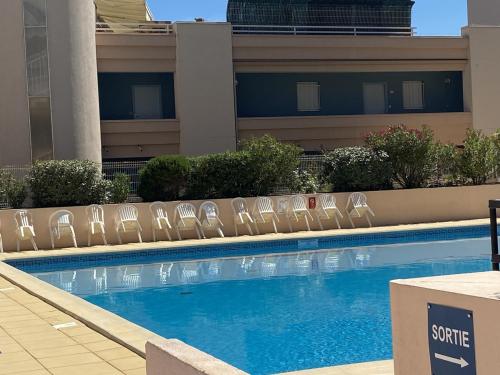 une piscine avec des chaises à côté d'un bâtiment dans l'établissement Appartement 2 Pièces avec Piscine et Parking à Sète - FR-1-338-480, à Sète