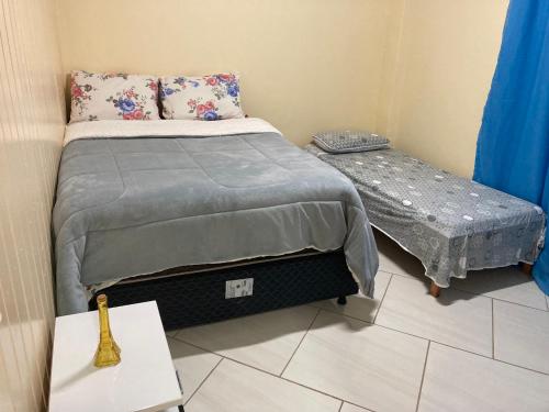 a small bedroom with a bed and a small table at Apartamento Cambara com churrasqueira e uma ampla sacada in Cambara do Sul