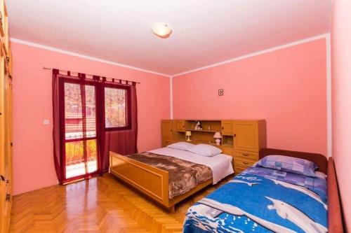 a bedroom with pink walls and a bed and a window at Apartments by the sea Vinisce, Trogir - 16860 in Vinišće