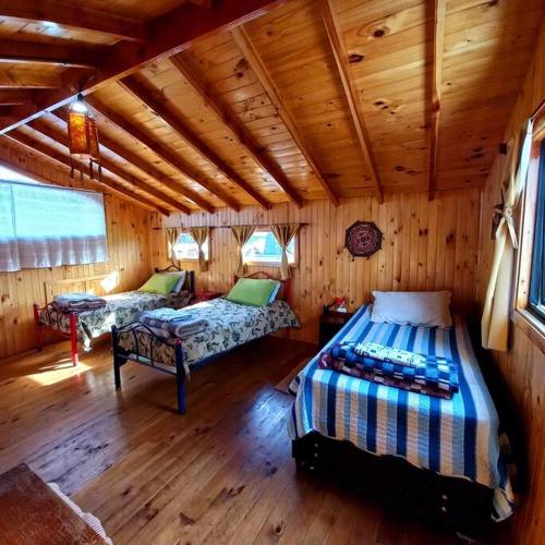 a bedroom with two beds in a wooden cabin at Cabañas Orillas del Lago in Panguipulli