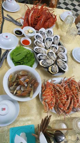 een tafel met borden met zeevruchten en kommen met eten bij Khách sạn Phương Dung in Cửa Lô