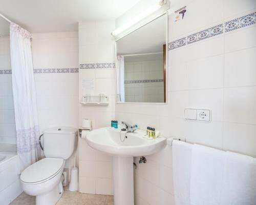 a white bathroom with a toilet and a sink at Hotel Orosol by Typic Hotels in San Antonio