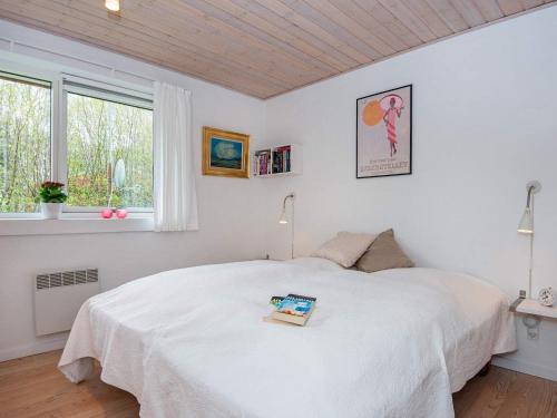 ein Schlafzimmer mit einem weißen Bett mit einem Buch darauf in der Unterkunft Holiday home Grenaa XLII in Brøndstrup