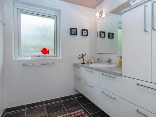 ein weißes Bad mit einem Waschbecken und einem Fenster in der Unterkunft Holiday home Grenaa XLII in Brøndstrup
