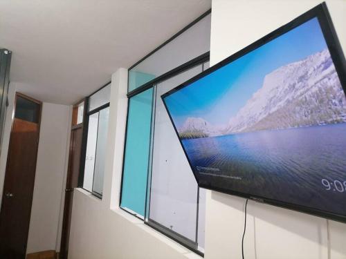 TV de pantalla plana grande en una pared con ventanas en Departamento Smart- Chiclayo B2 en Chiclayo