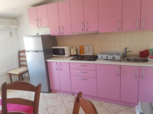cocina con armarios rosados y nevera blanca en Apartments by the sea Sevid, Trogir - 16802, en Marina