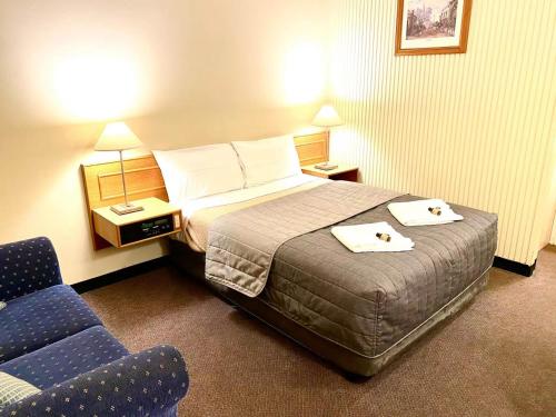 a hotel room with a bed and two chairs at Gateway Motor Inn in Narrandera