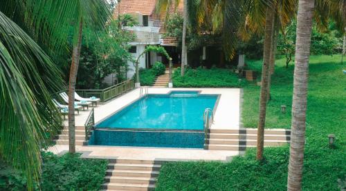 una piscina in un cortile con palme di Aanandakosha Ayurveda Retreat a Trivandrum