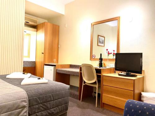 a hotel room with a bed and a desk with a television at Gateway Motor Inn in Narrandera