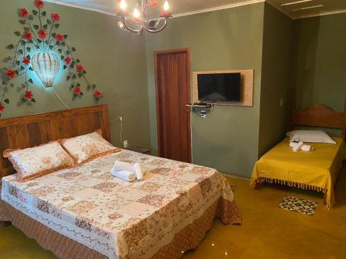 ein Schlafzimmer mit einem Bett und einem TV an der Wand in der Unterkunft Pouso da Olimpia in Tiradentes
