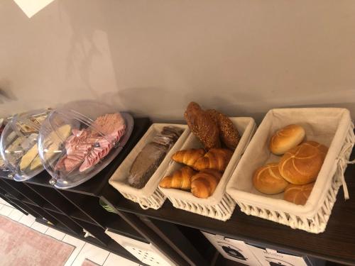 two trays of bread and pastries on a shelf at Pension Claudia in Vösendorf