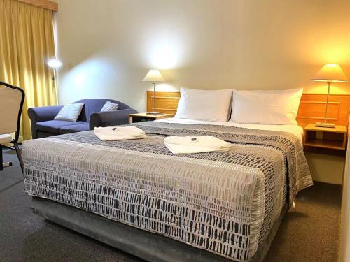 a hotel room with a bed and a chair at Gateway Motor Inn in Narrandera