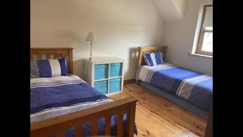 a bedroom with two beds and a lamp in it at Beautiful Central 3-Bed House in Co Clare in Milltown Malbay