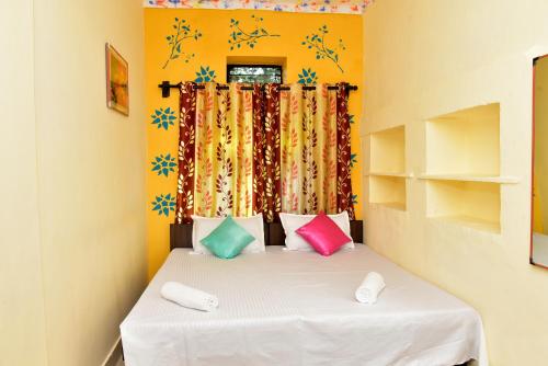 een kleine slaapkamer met een bed met kleurrijke kussens bij Hotel Moon Light in Pushkar