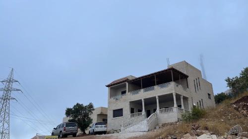 un edificio en una colina con coches estacionados frente a él en Furnished house بيت مفروش ابو فارس, en Ajloun