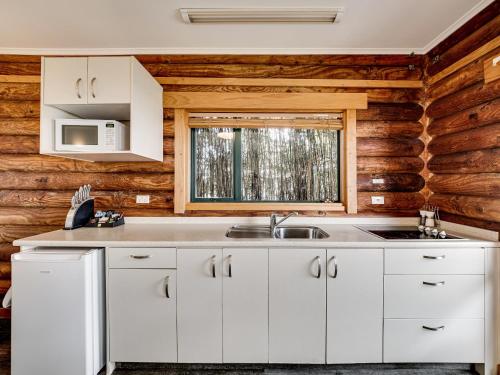 a kitchen with white cabinets and a window at Shining Star Beachfront Accommodation in Hokitika