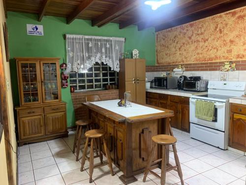 a kitchen with green walls and a island with stools at Gardens House, Airport Juan Santamaría, Alajuela, San José in Alajuela City