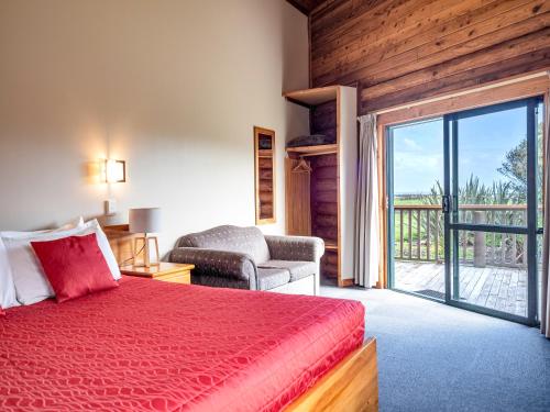 a bedroom with a red bed and a sliding glass door at Shining Star Beachfront Accommodation in Hokitika