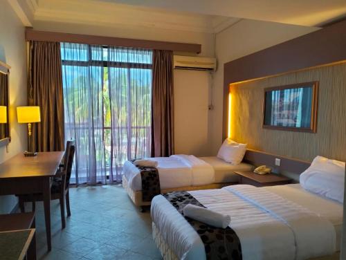 Habitación de hotel con 2 camas y escritorio en THE CLOVE MONT HOTEL, en Kampung Gurun
