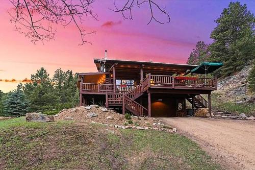 a house on top of a hill with a sunset at Classic Log Cabin near Rocky Mountain National Park and near Skiing in Lyons
