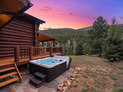 a hot tub on a deck next to a cabin at Classic Log Cabin near Rocky Mountain National Park and near Skiing in Lyons