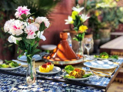 una mesa con platos de comida y flores. en Riad Al Mamoune en Marrakech