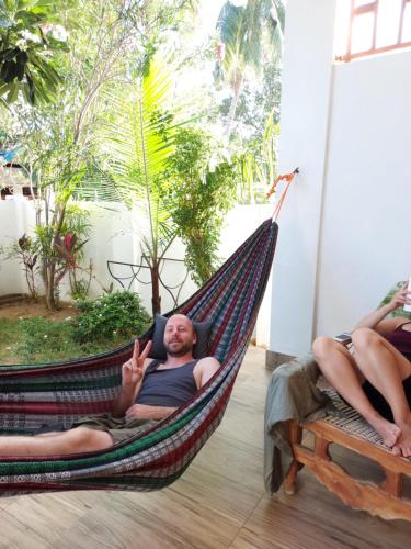 a man laying in a hammock with two women at Aqua Blue in Arugam Bay
