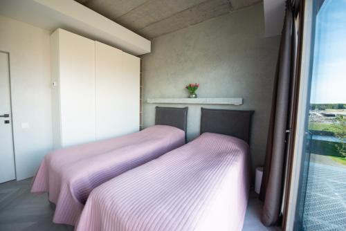 Un dormitorio con una cama con sábanas moradas y una ventana en MARINIS Luxury Apartments - Svencelės Vėjai - 1st line by the Lagoon, en Svencelė